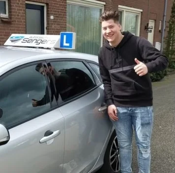 Geslaagde leerling met de sleutels naast de lesauto van Autorijschool Sengers