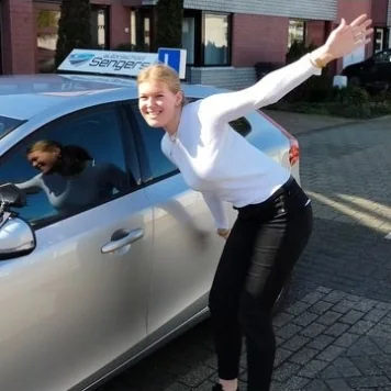 Geslaagde leerling juicht naast de lesauto van Autorijschool Sengers