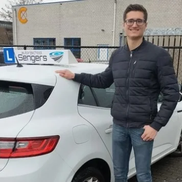 Geslaagde leerling leunt op de lesauto van Autorijschool Sengers