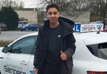 Geslaagde leerling met duim omhoog naast de lesauto van Autorijschool Sengers